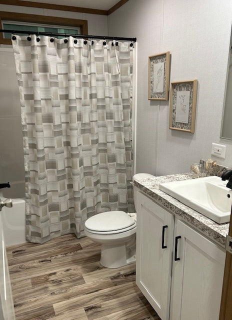 Bathroom with a patterned shower curtain, toilet, and sink.