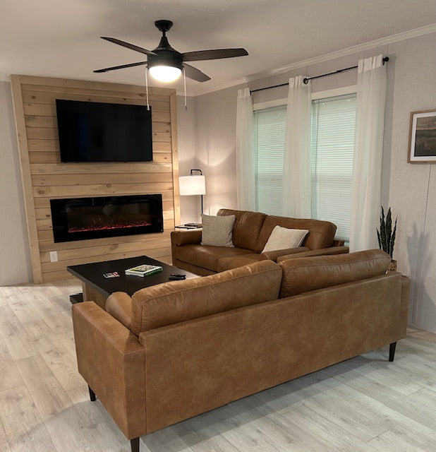 Living room with brown leather sectional sofa, coffee table, and wall-mounted TV.