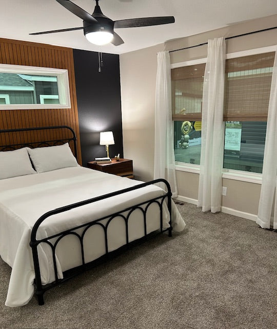 Bedroom with a black metal bed frame, white bedding, and a nightstand.
