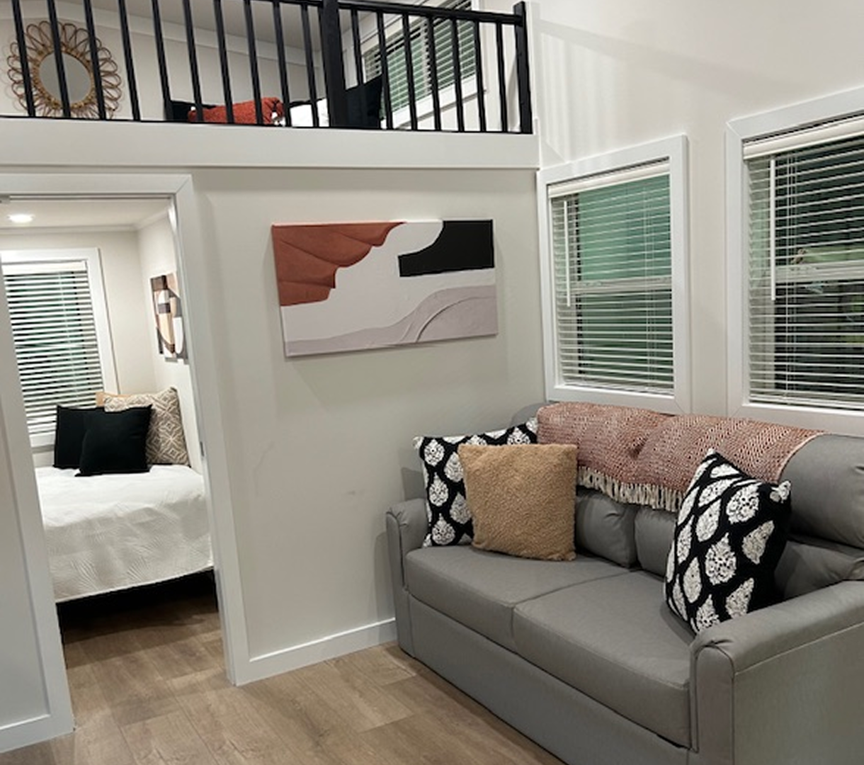 Living room with gray sofa, decorative pillows, and a view into a bedroom.