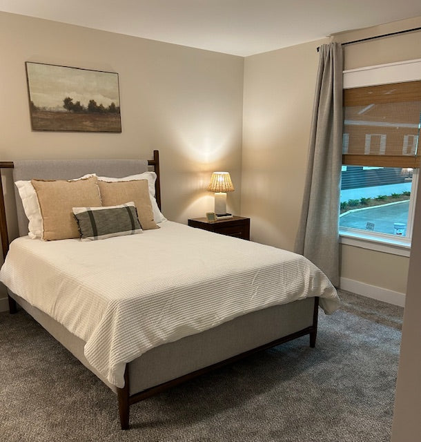 Bedroom with a bed, nightstand, lamp, and window view.