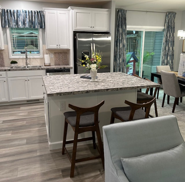 Modern kitchen with marble island, stainless steel appliances, and wooden chairs.