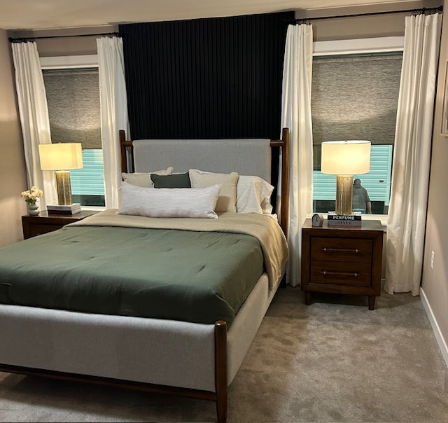 Neatly made bed in a bedroom with two lamps and curtains.